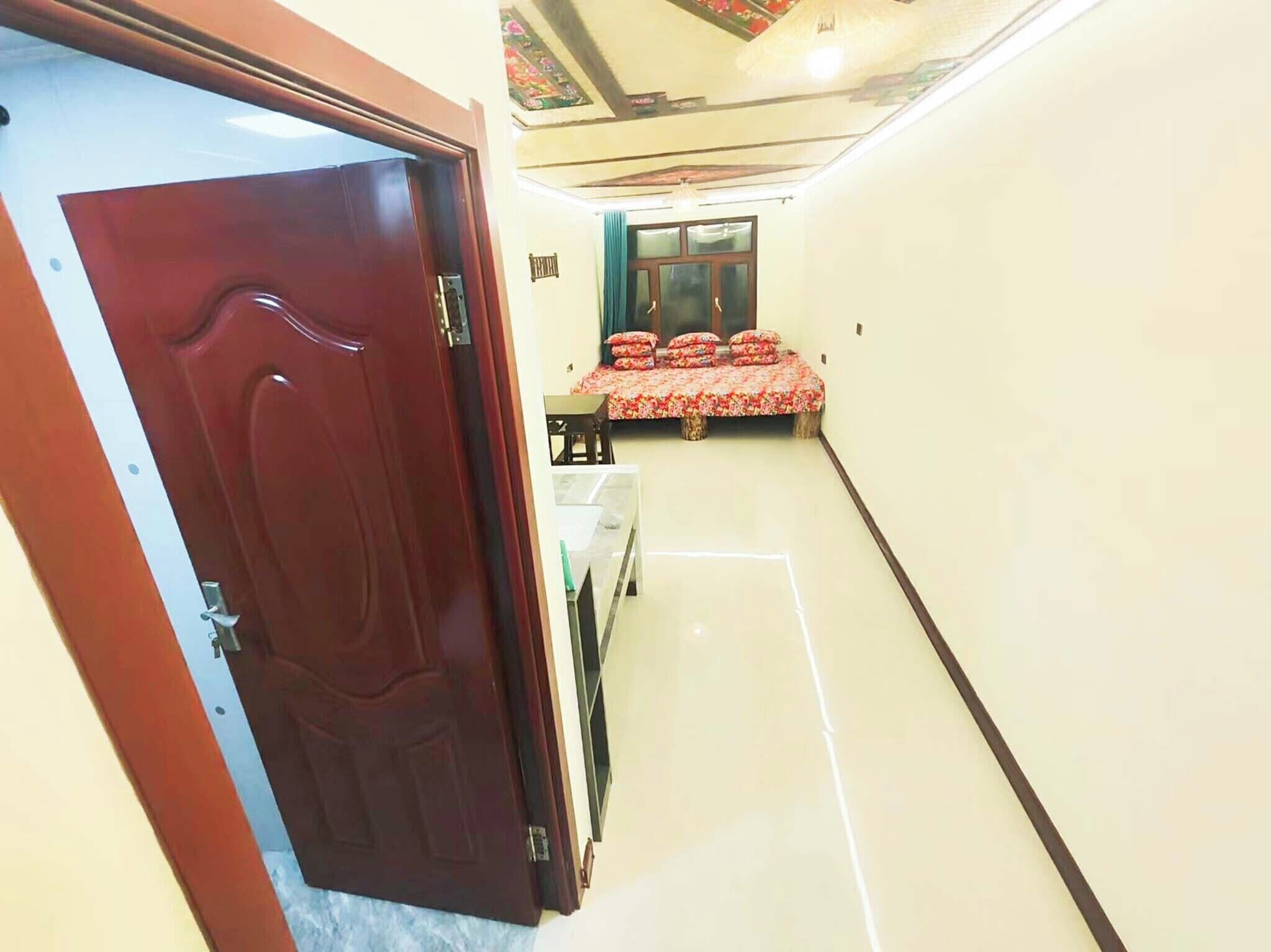 A room with a bed, a window with curtains, and a door.