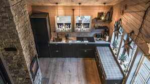 Cocina compacta con una isla central, suelo de madera y una pared decorativa de piedra.