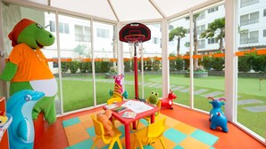 A children's play area with colorful toys, a basketball hoop, and a view of a residential building. - Horison Ultima Sentraland Semarang (Semarang)