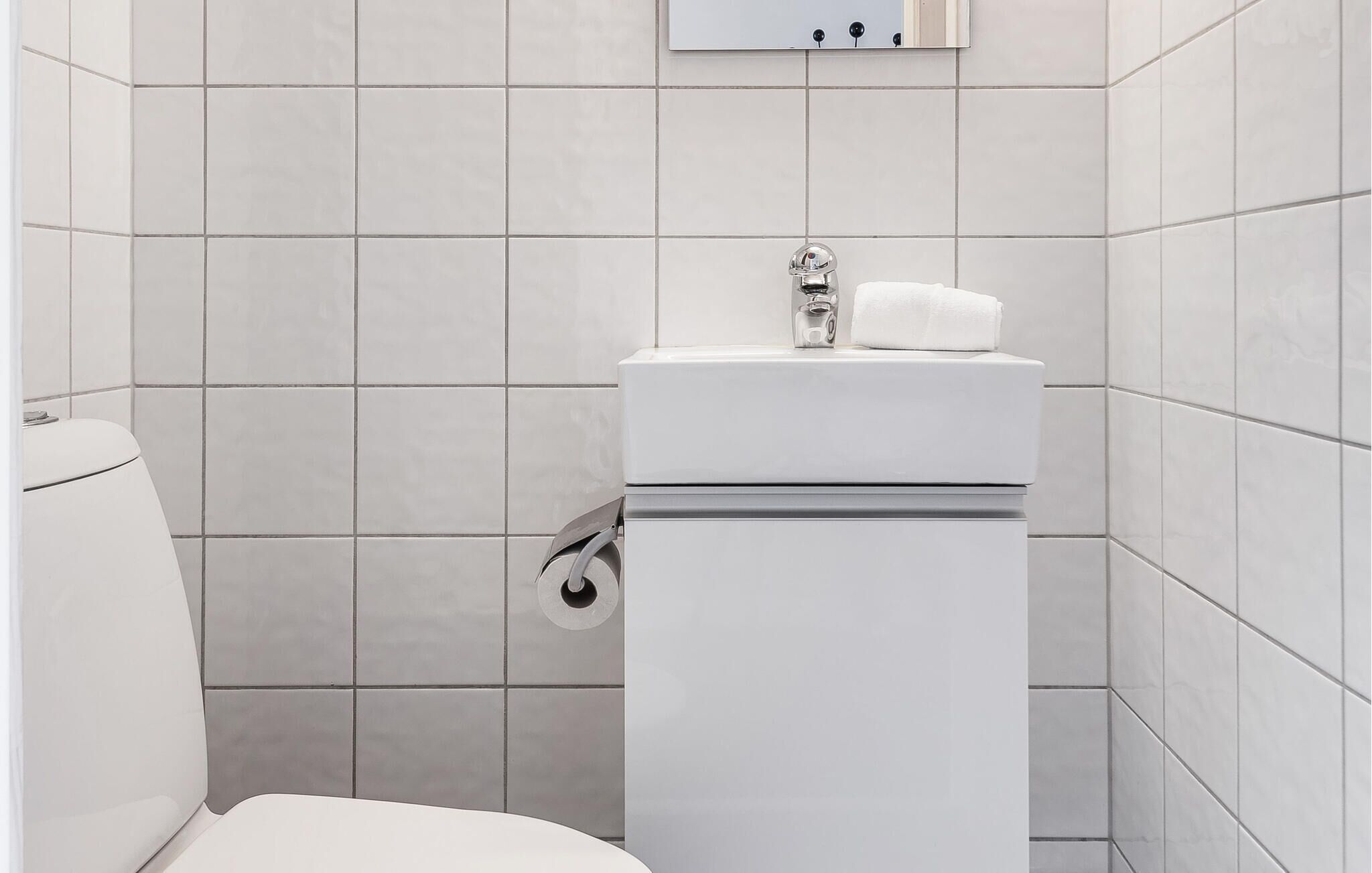Une salle de bain moderne avec des toilettes, un lavabo et un miroir.