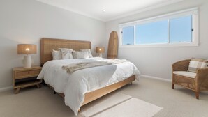 A bedroom with a large bed, bedside tables, a chair, and a window. - Ruby Jade Coastal Luxury at Anna Bay (Anna Bay)