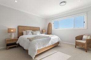 Ein Schlafzimmer mit einem großen Bett, Nachttischen, einem Sessel und einem Fenster.