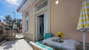 A patio with a table set for two, a chair, and a yellow-striped umbrella. - Amalija Sea View Studio  Apartment 4, Mali Lošinj, Croatia (Mali Lošinj)
