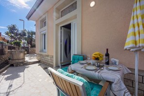 A patio with a table set for dining, a chair, and a small fountain. - Amalija Sea View Studio  Apartment 4, Mali Lošinj, Croatia (Mali Lošinj)