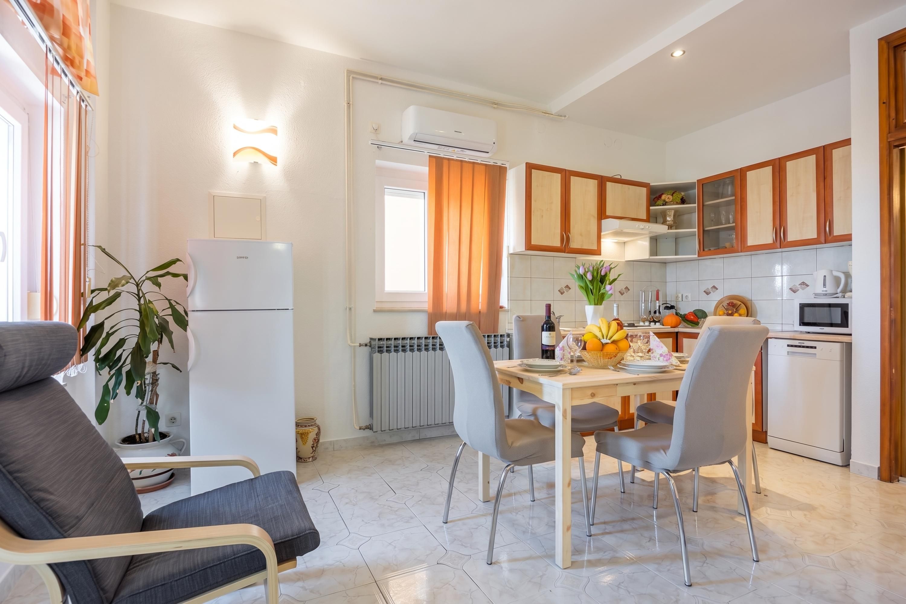 A modern kitchen with a dining area, featuring a refrigerator, stove, microwave, and cabinets.