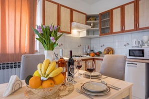 A kitchen with wooden cabinets, a dining table set with plates, glasses, and a fruit bowl.