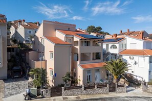 A residential area with multi-story buildings, a paved street, and a palm tree.