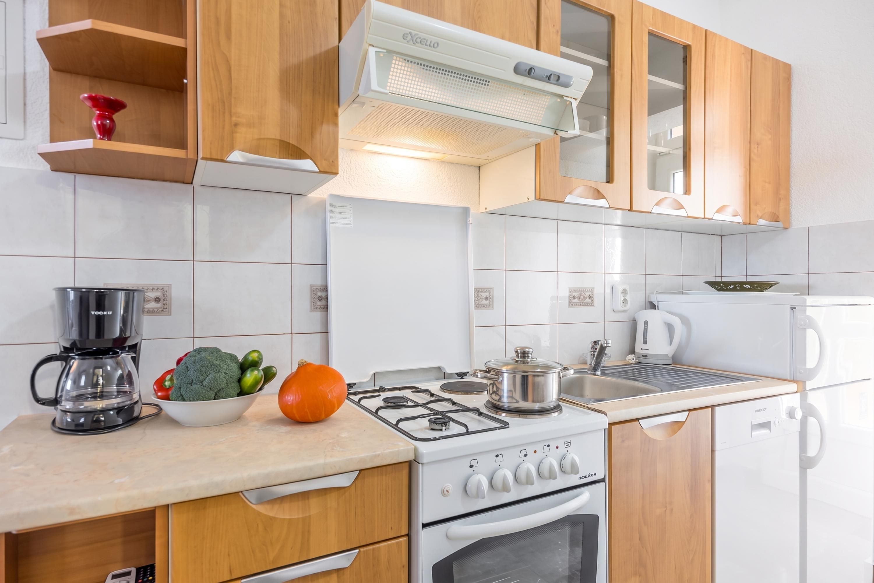 Une cuisine moderne avec des meubles en bois, une cuisinière à gaz, un four encastré et une machine à café.
