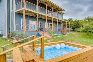 Une maison à deux étages avec une terrasse en bois, une piscine et un balcon.