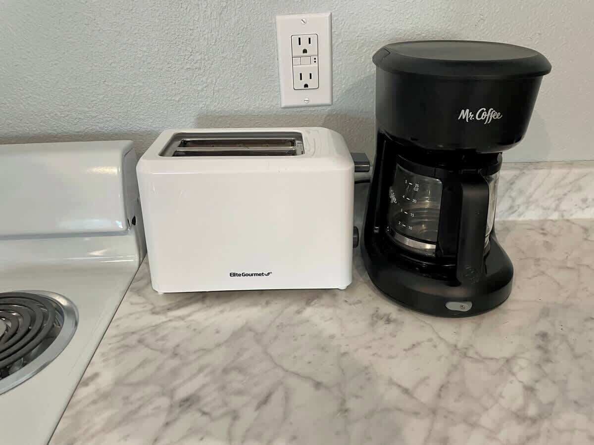 A white toaster and a black Mr. Coffee coffee maker on a marble countertop.