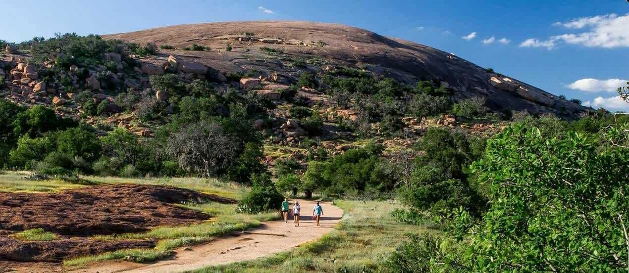A natural landscape with a hill, a dirt path, and some greenery.