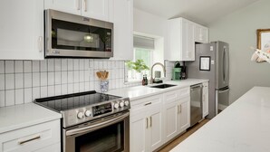 A modern kitchen with white cabinetry, a stainless steel range, a built-in microwave, a dishwasher, and a refrigerator. - Two Houses, POOL, shared backyard 8bed/4bath (Blanco)