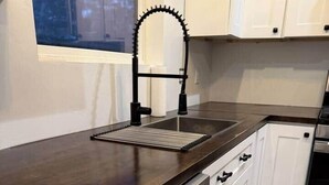 Une cuisine moderne avec des armoires blanches, un lave-vaisselle en acier inoxydable et un plan de travail en bois foncé.
