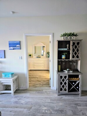 A room with a wooden floor, a white cabinet with glass doors, and a mirror above a white dresser.
