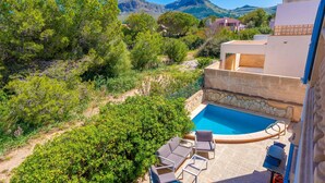 A pool area with lounge chairs, surrounded by greenery and a mountain view. - PUNTA LLARGA - Cozy house with sea views, private pool and free Wi-Fi (Artà)