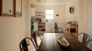 Una cocina moderna con armarios blancos, una mesa de comedor de madera y una lámpara colgante.
