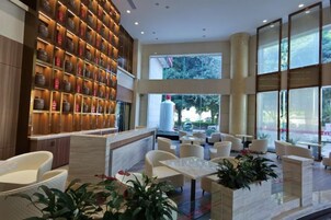 Un hall de hotel con mostrador de recepción, zona de estar y amplias ventanas.