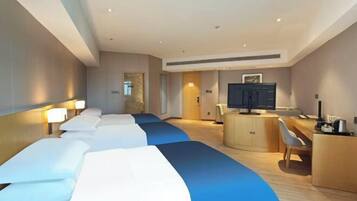 Quarto de hotel com uma cama grande, uma escrivaninha, uma televisão e um armário.