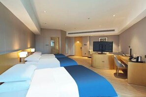Una habitación de hotel con una cama grande, un escritorio, un televisor y un armario.