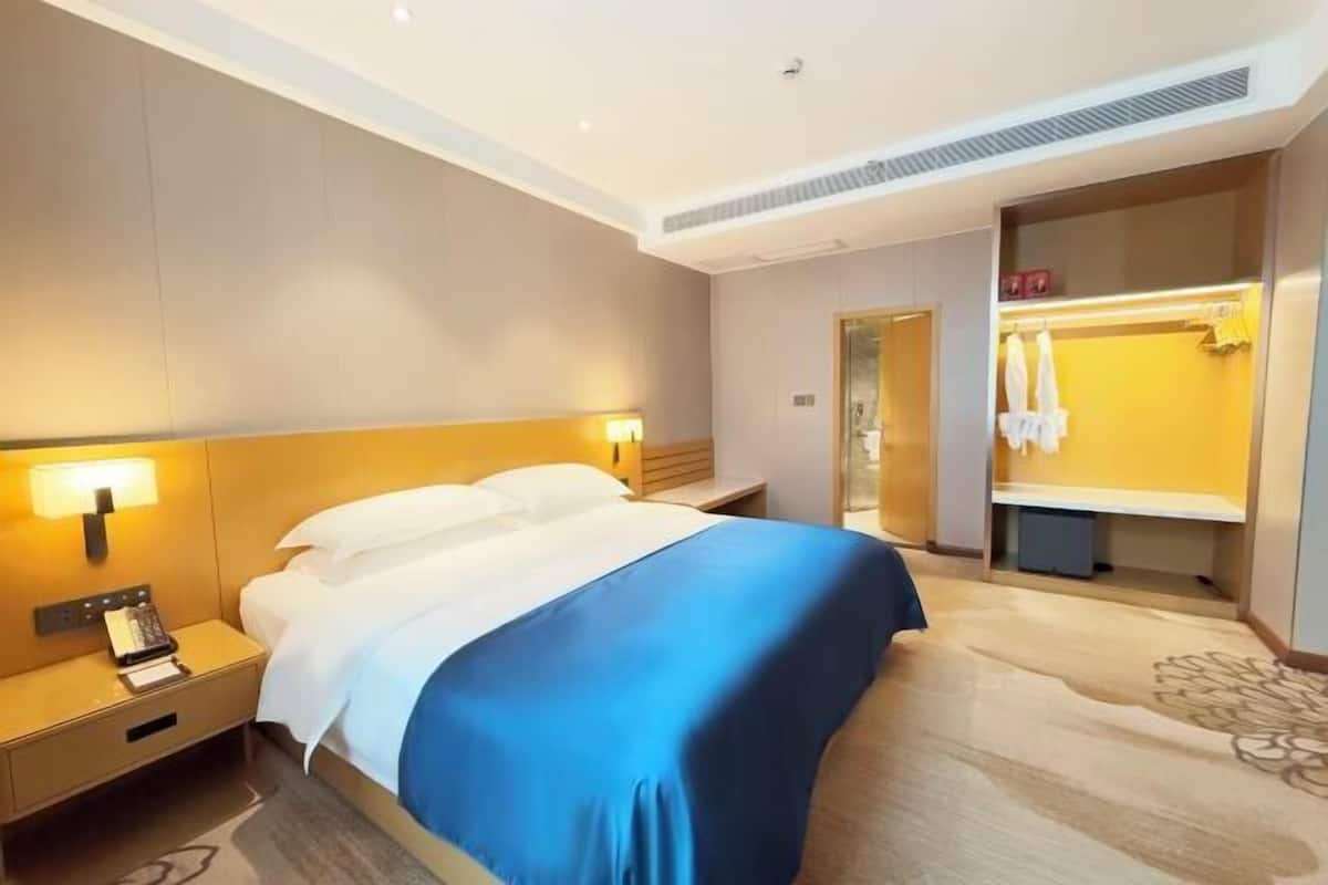A hotel room with a bed, bedside table, lamp, and a mirror.