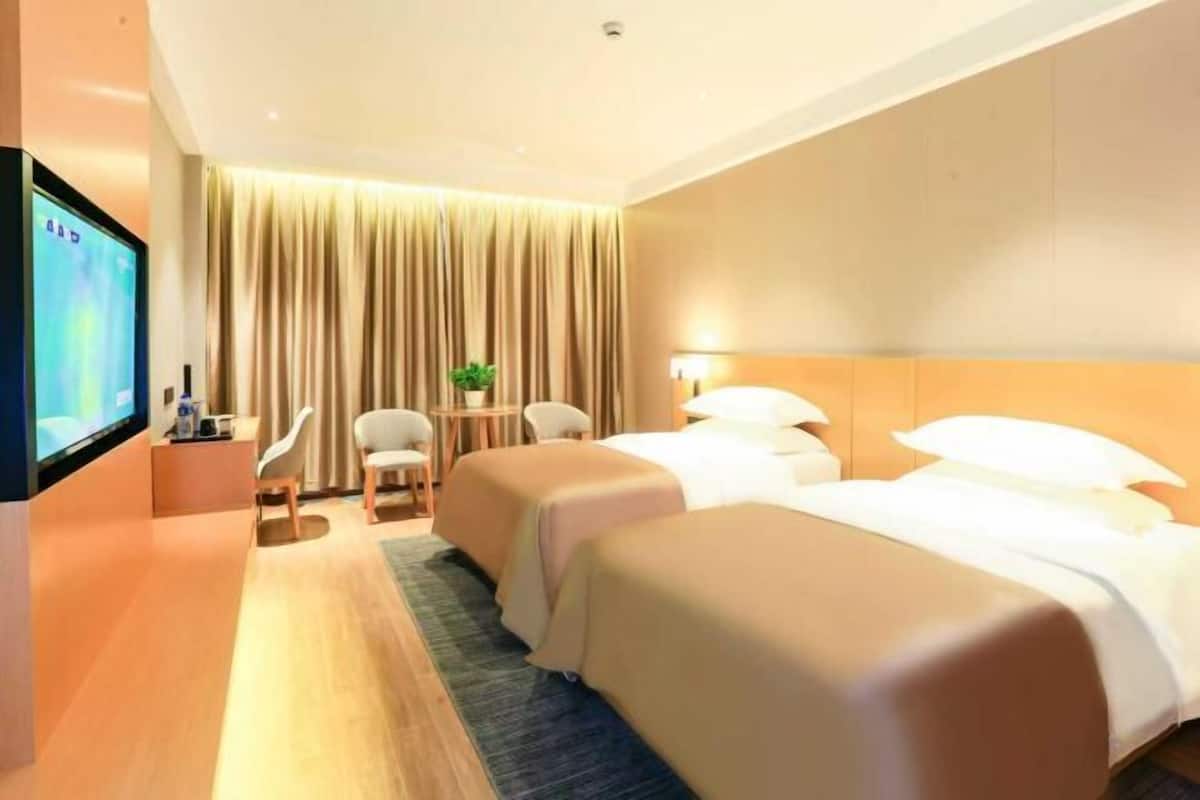 A hotel room with two beds, a TV, a desk, and a chair.