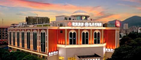 A hotel with a prominent dome and arched windows, a large entrance, and a parking area.