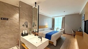 A hotel room with a large bed, a bathroom with a mirror and sink, a desk, and a TV. - Guiping Ruquan Jingliugang Hotel (Xishan Branch) (Guiping)