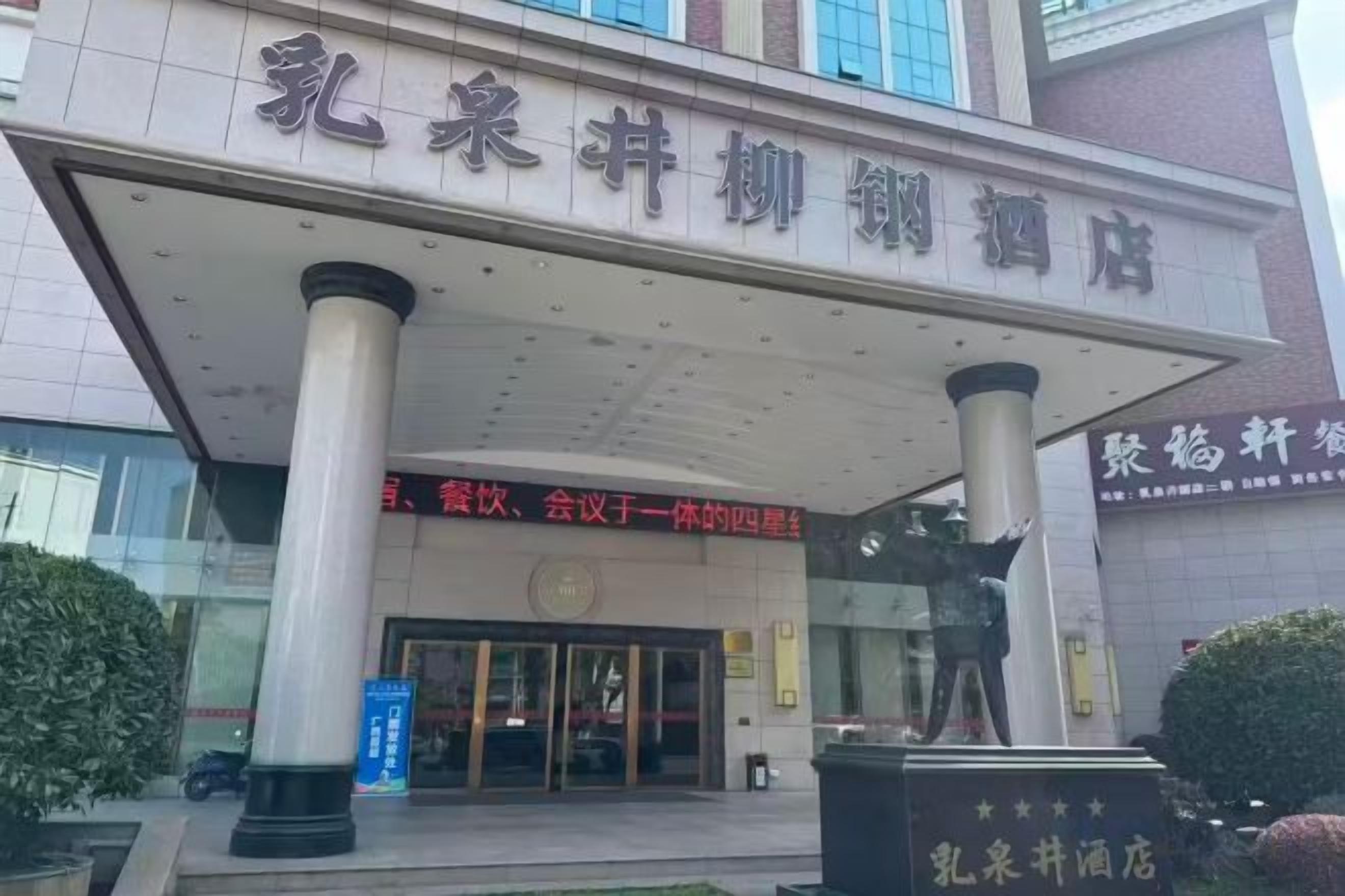 A hotel entrance with a covered entrance area, columns, and a signboard.
