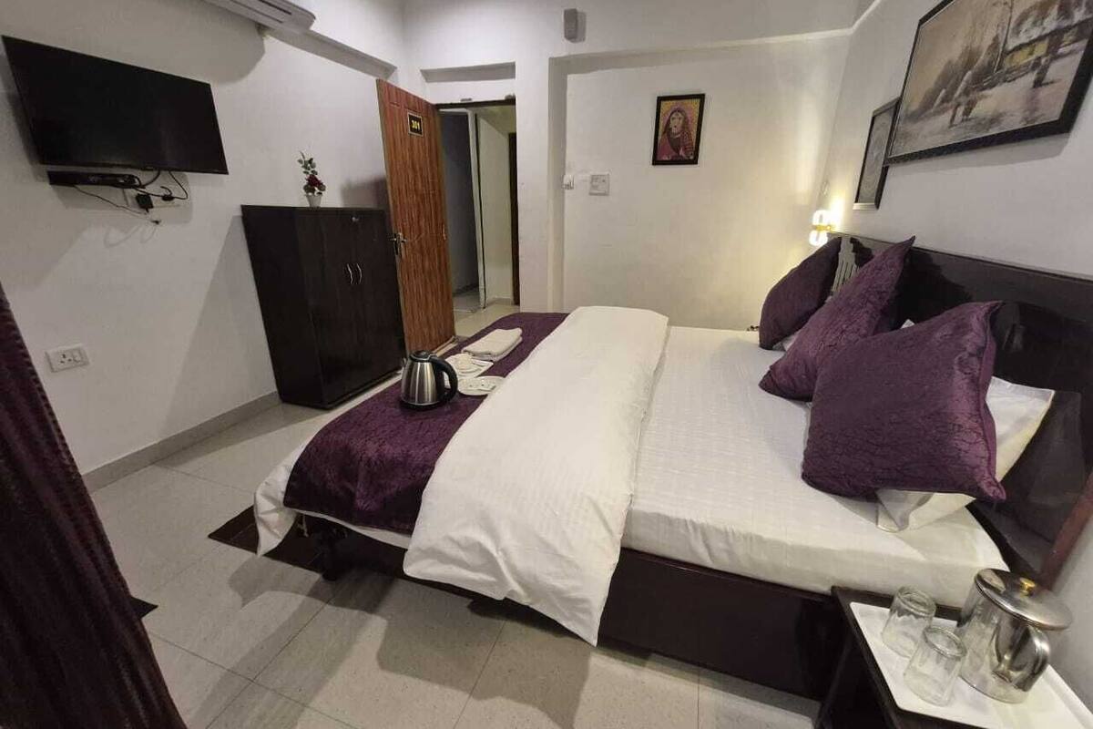Een hotelkamer met een bed, een televisie, een kledingkast en een nachtkastje met een lamp.