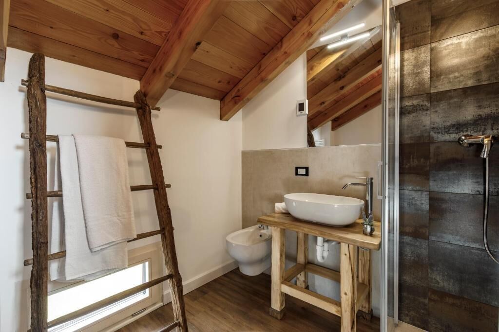 Un baño con una escalera de madera, un bidé, un lavabo y una ducha.