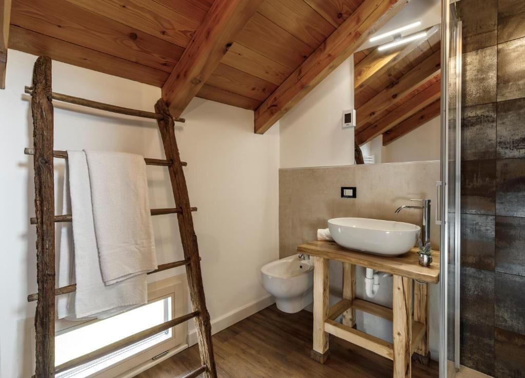 Un bagno con una scala in legno, un lavandino bianco e un bidet.