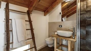 Un bagno con una scala in legno, un lavandino bianco e un bidet.