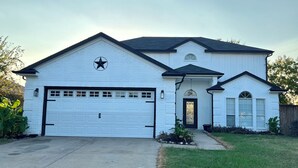 A two-story house with a garage, a front porch, and a small attached structure.