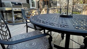 Eine Terrasse mit einem runden Tisch und Stühlen, einem Grill und einer Laterne.