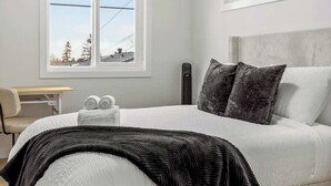 A bedroom with a bed, a window, a bedside table, and a radiator. - AC, 95 min Banff, Local Coffee,Walk to Restaurants (Calgary)