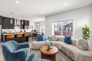 Een moderne woonkamer met een bank, stoelen en een salontafel.