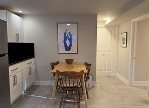 A modern kitchen with white cabinets, a black countertop, and a wooden dining table with chairs. - Beautiful condo - WALK to Oakland’s best offerings ! (Oakland)