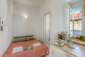 A bedroom with a bed, a bedside table with a tray of food, a window, and a door. - Appartamento Villa Mary - Sea View & Balcony (Sanremo)
