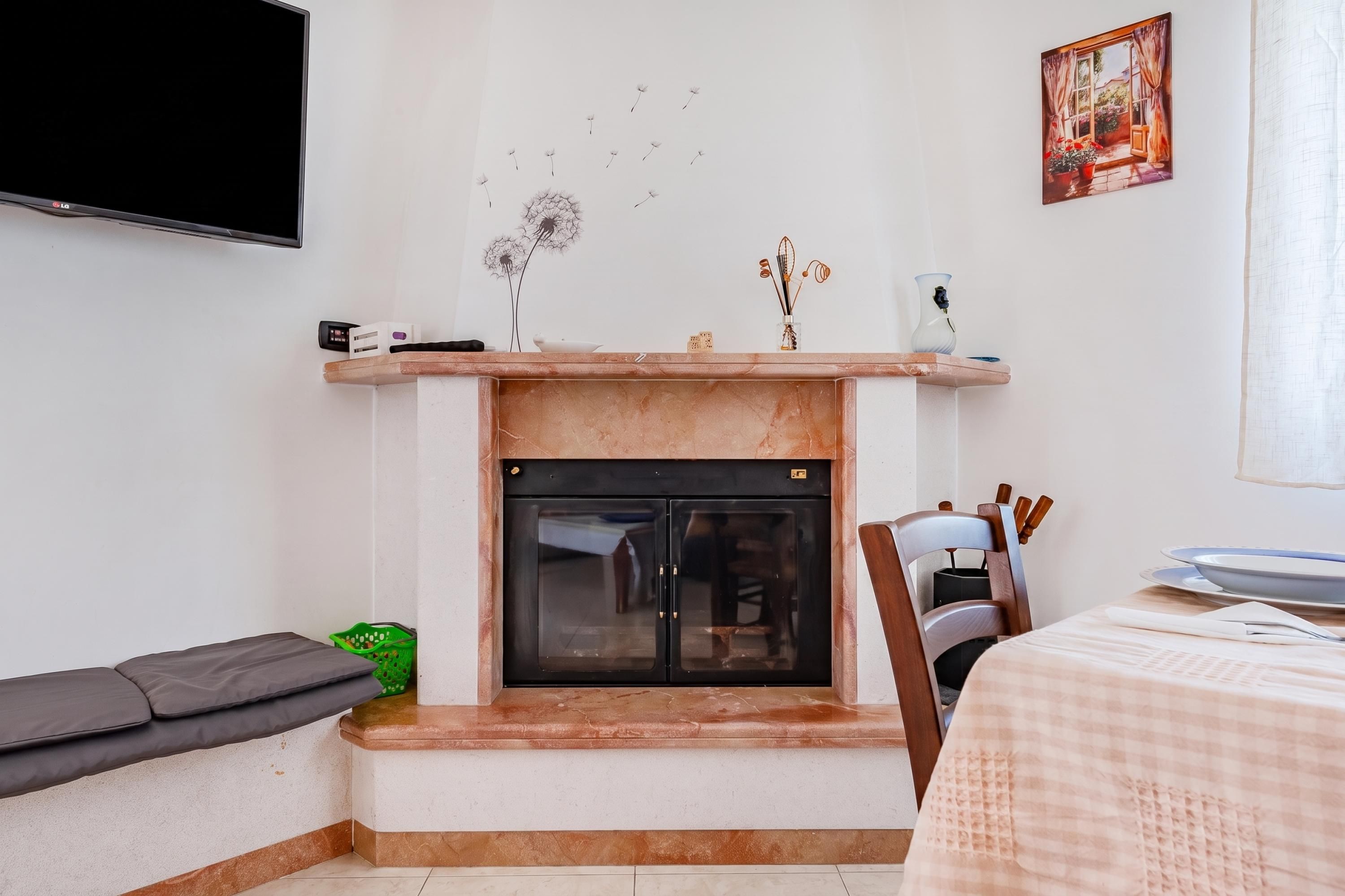 Sala de estar com lareira, televisão de tela plana na parede e área de jantar com mesa posta para dois.