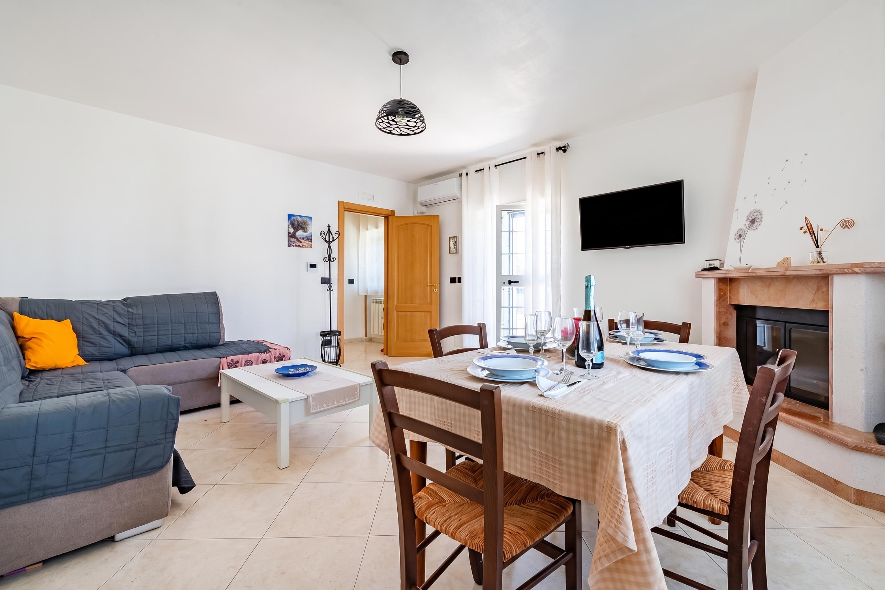Un salon avec un canapé, une table à manger dressée pour quatre personnes et une cheminée.