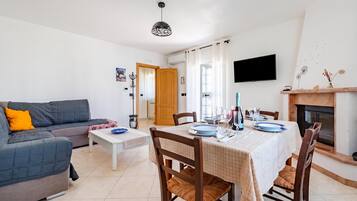 Una sala de estar con sofá, una mesa de comedor para cuatro personas y una chimenea.