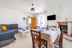 A living room with a sofa, a dining table set for four, and a fireplace. - Bianca Olive House - Alberobello (Alberobello)