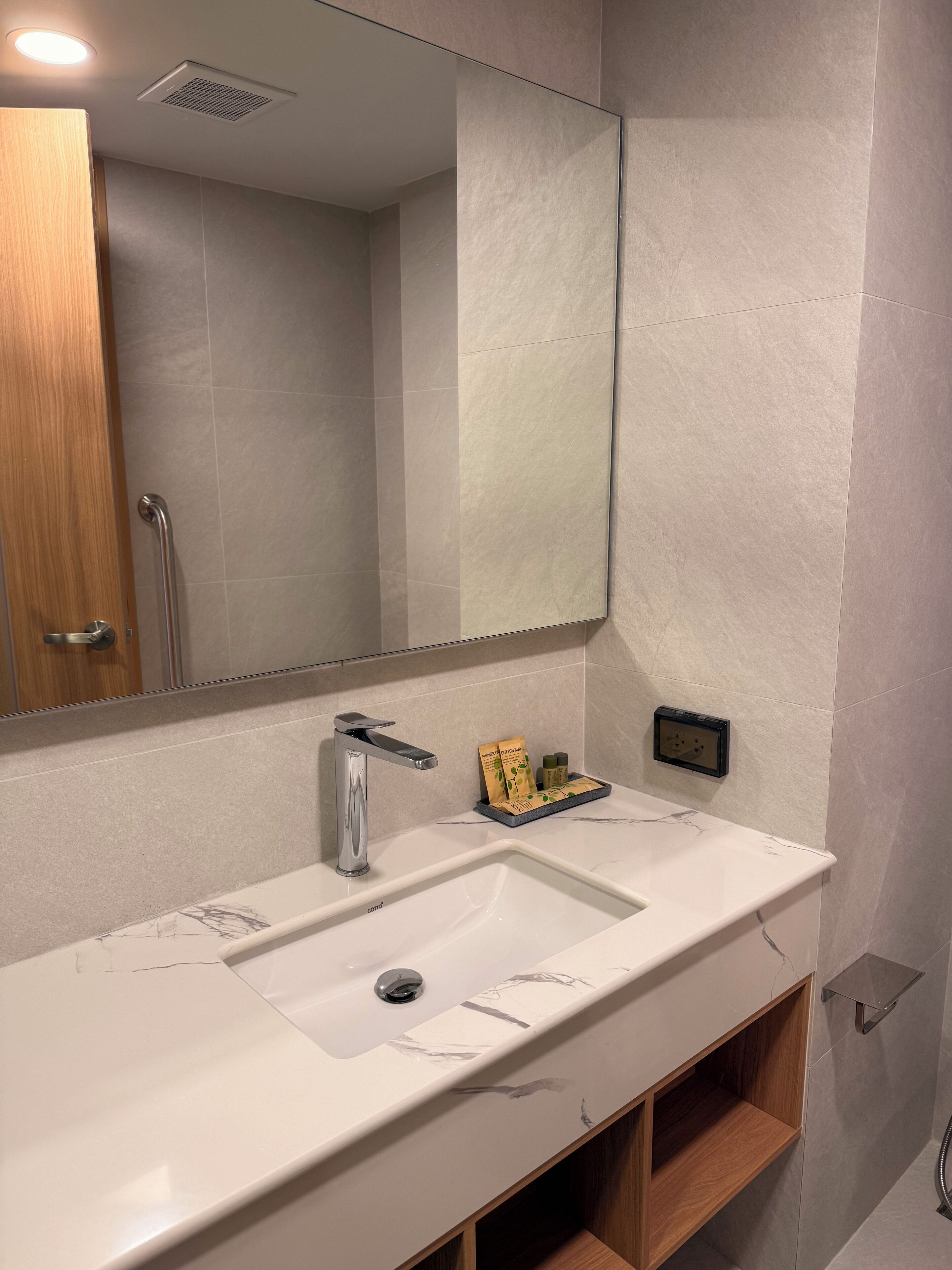 Un baño moderno con un lavamanos blanco, un espejo y un mueble de madera.