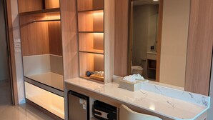A modern bathroom with a large mirror, wooden cabinetry, and a built-in sink. - Aston Hotel Pattaya (Pattaya)