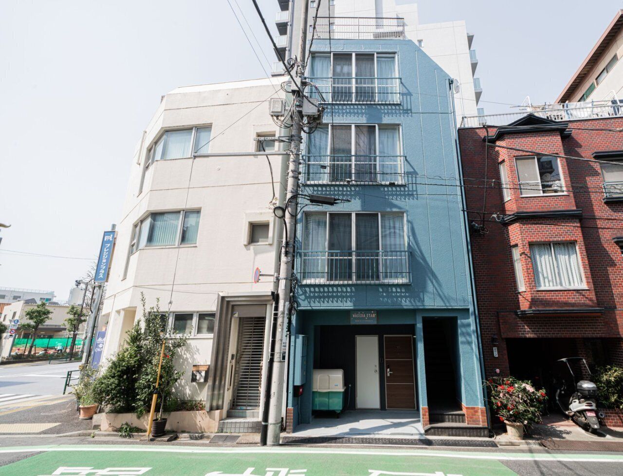 A multi-story building with a blue storefront, a visible entrance, and a parking area.