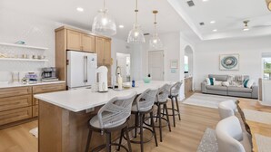 Una cocina moderna con una isla central, taburetes de bar e iluminación colgante.