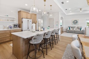 A modern kitchen with a central island, bar stools, and pendant lighting. - New Listing! Private Pool, Putt Putt Green, Bikes & Nearby Beach! (Panama City Beach)
