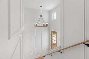 A staircase with a wooden handrail, white walls, and a chandelier. - New Listing! Private Pool, Putt Putt Green, Bikes & Nearby Beach! (Panama City Beach)