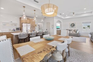A modern kitchen with wooden cabinets, a dining table with white chairs, and pendant lighting. - New Listing! Private Pool, Putt Putt Green, Bikes & Nearby Beach! (Panama City Beach)