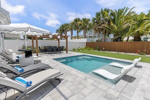 A swimming pool with lounge chairs, a pergola with string lights, and palm trees. - New Listing! Private Pool, Putt Putt Green, Bikes & Nearby Beach! (Panama City Beach)